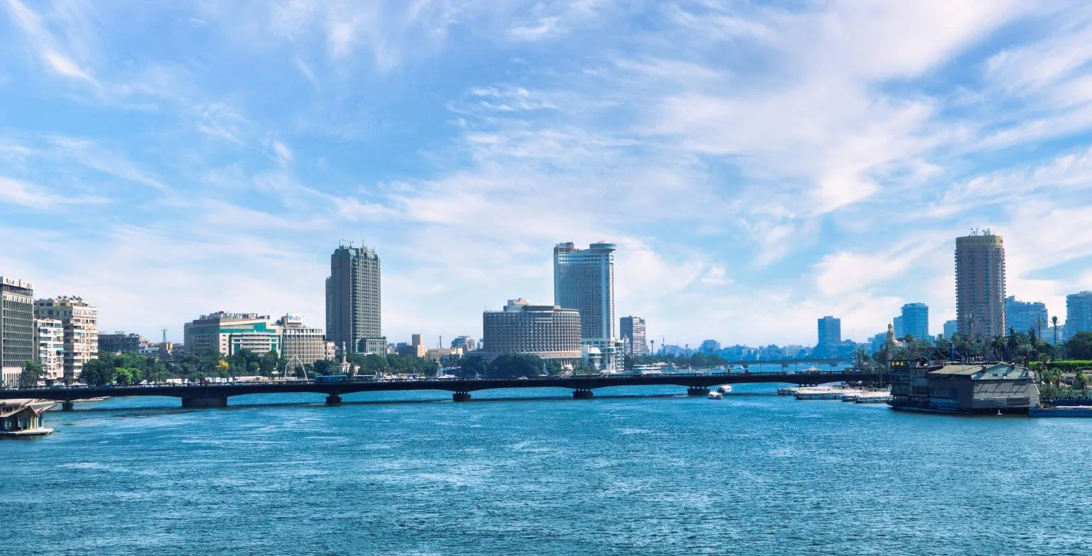 Modern Cairo skyline with a bridge over the Nile River under a blue sky