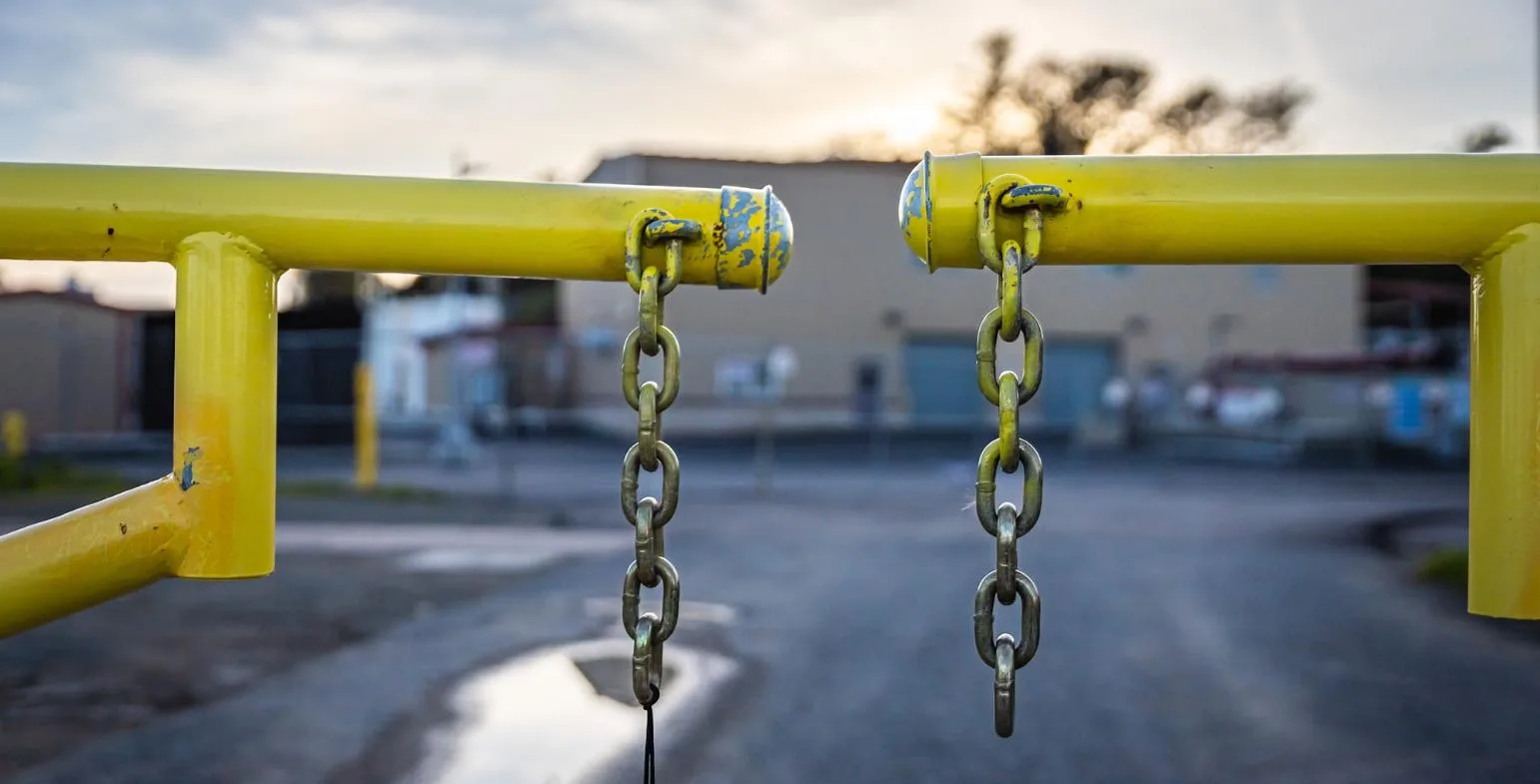 Two disconnected chains hanging from a barrier, symbolising broken links