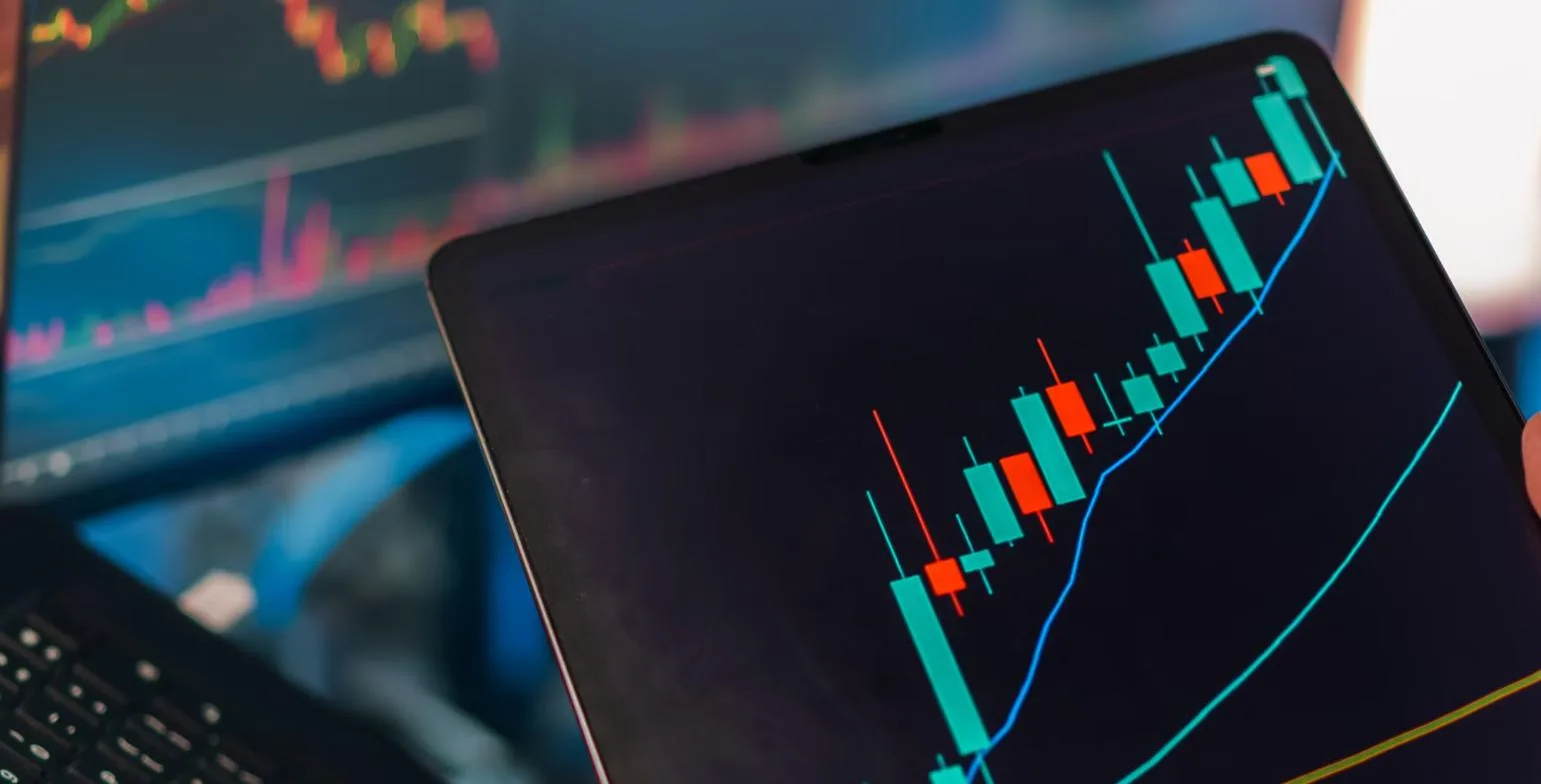 Tablet displaying a rising green and red candlestick trading chart