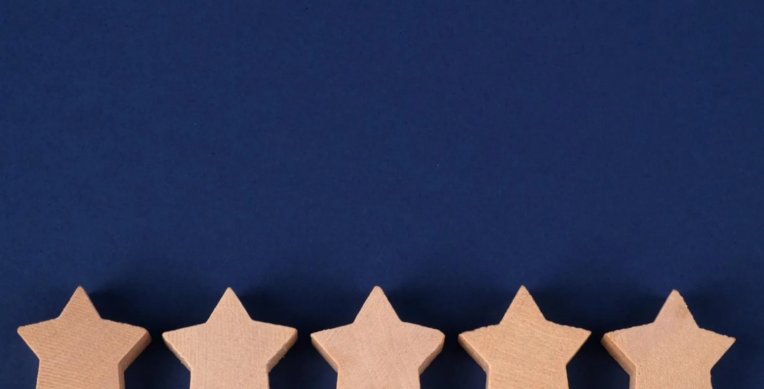 Row of five wooden star shapes on a navy blue background