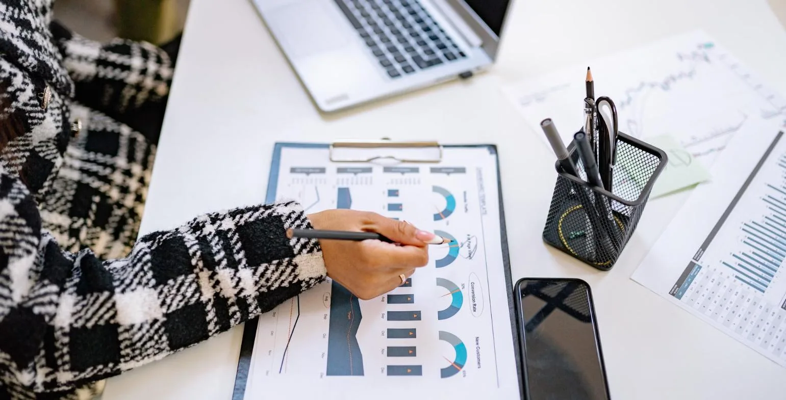 Marketer reviewing conversion rate and new customer charts on a printed report