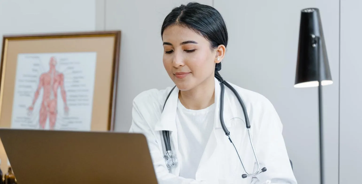 Doctor working on a laptop in a clinic consultation room