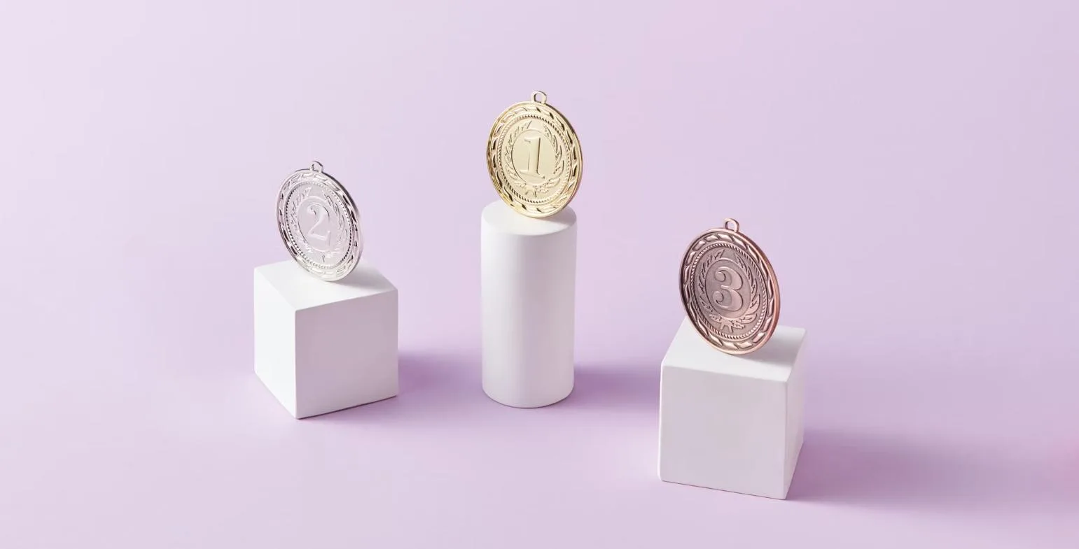 Gold, silver, and bronze medals displayed on white podium blocks representing first, second, and third place rankings