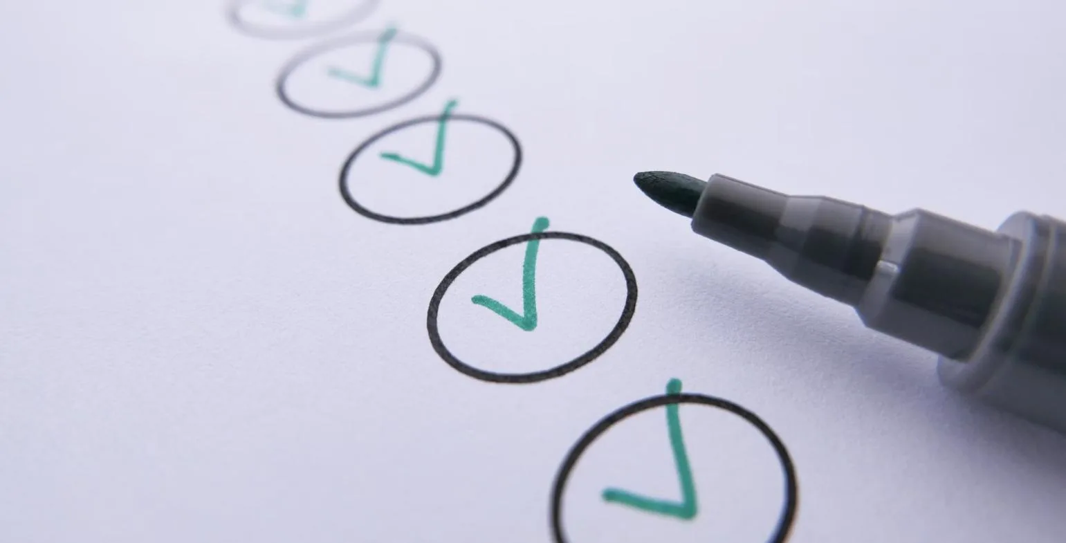 Row of green ticks drawn in circles on paper beside a marker pen