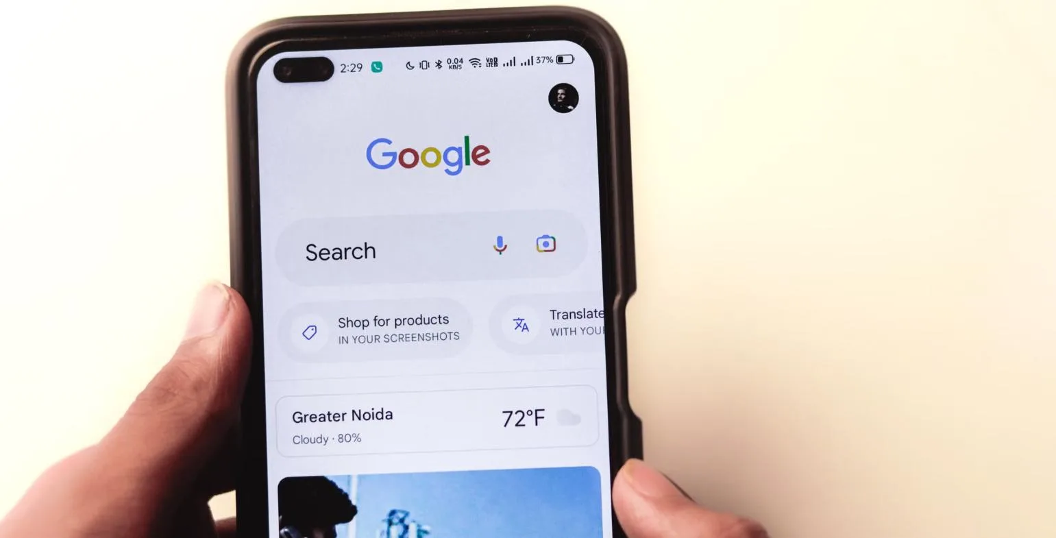 Hand holding a smartphone displaying the Google search homepage