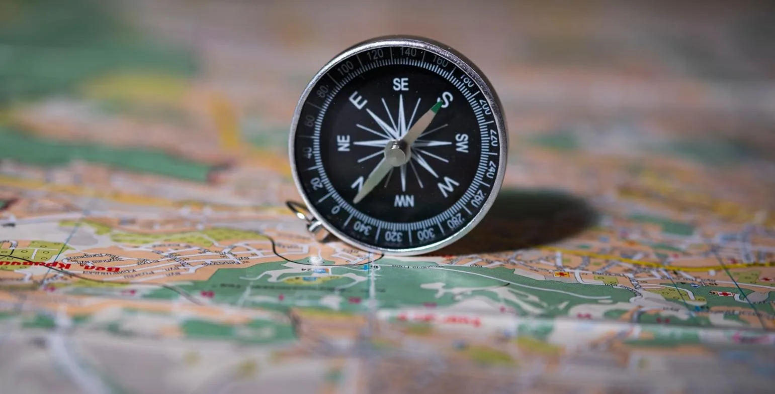 Compass resting on a colourful paper map