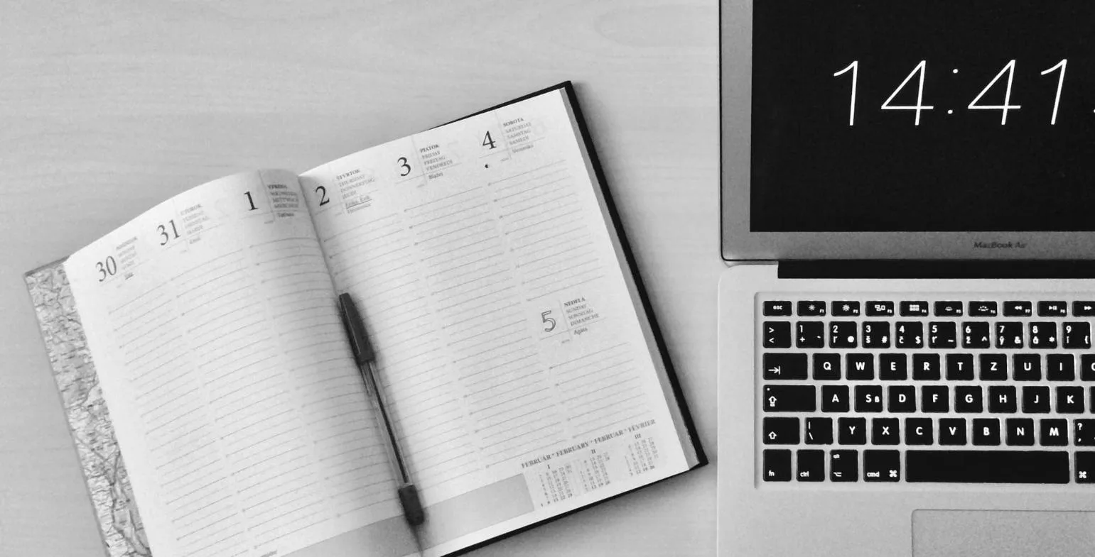 Open daily planner beside a laptop displaying the time, representing an SEO timeline