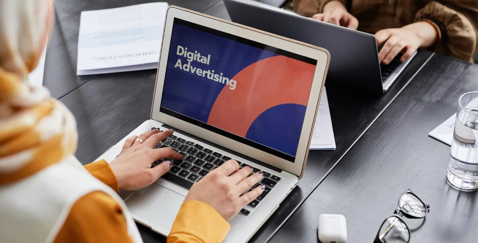 Marketer working on a laptop showing a Digital Advertising presentation slide