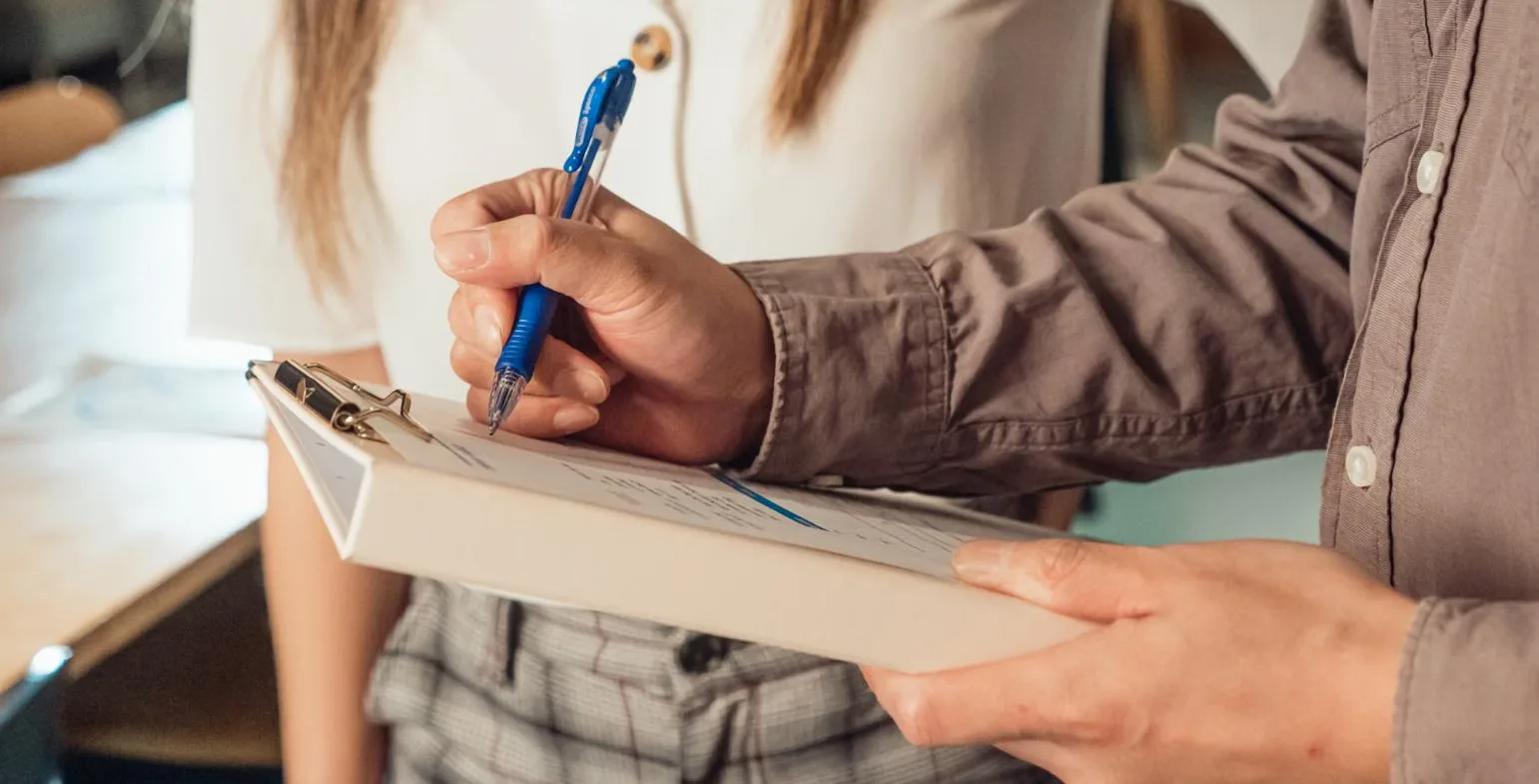 Person filling in a checklist on a clipboard while vetting a guest posting site