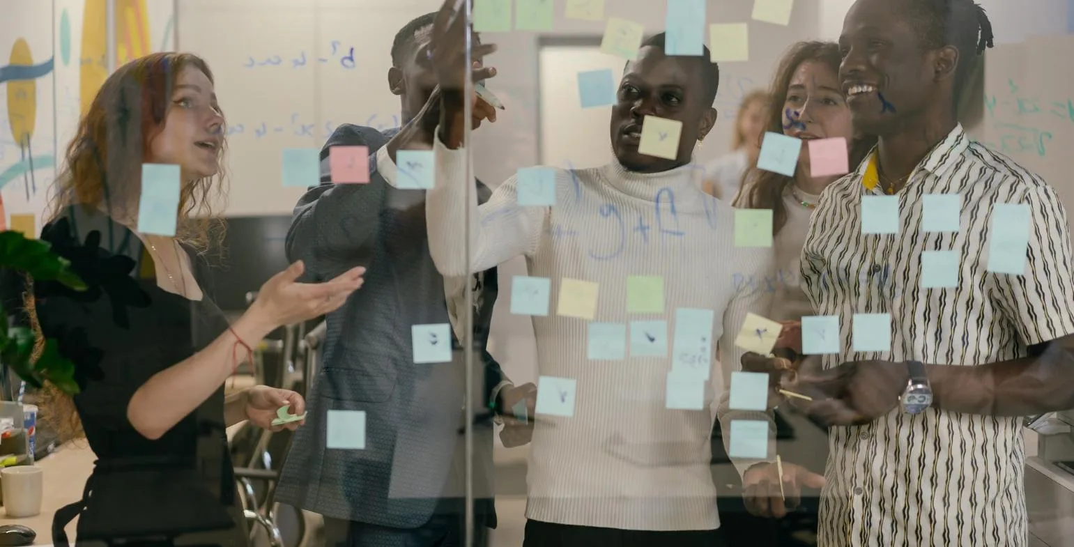 Agency team collaborating behind a glass wall covered in coloured sticky notes