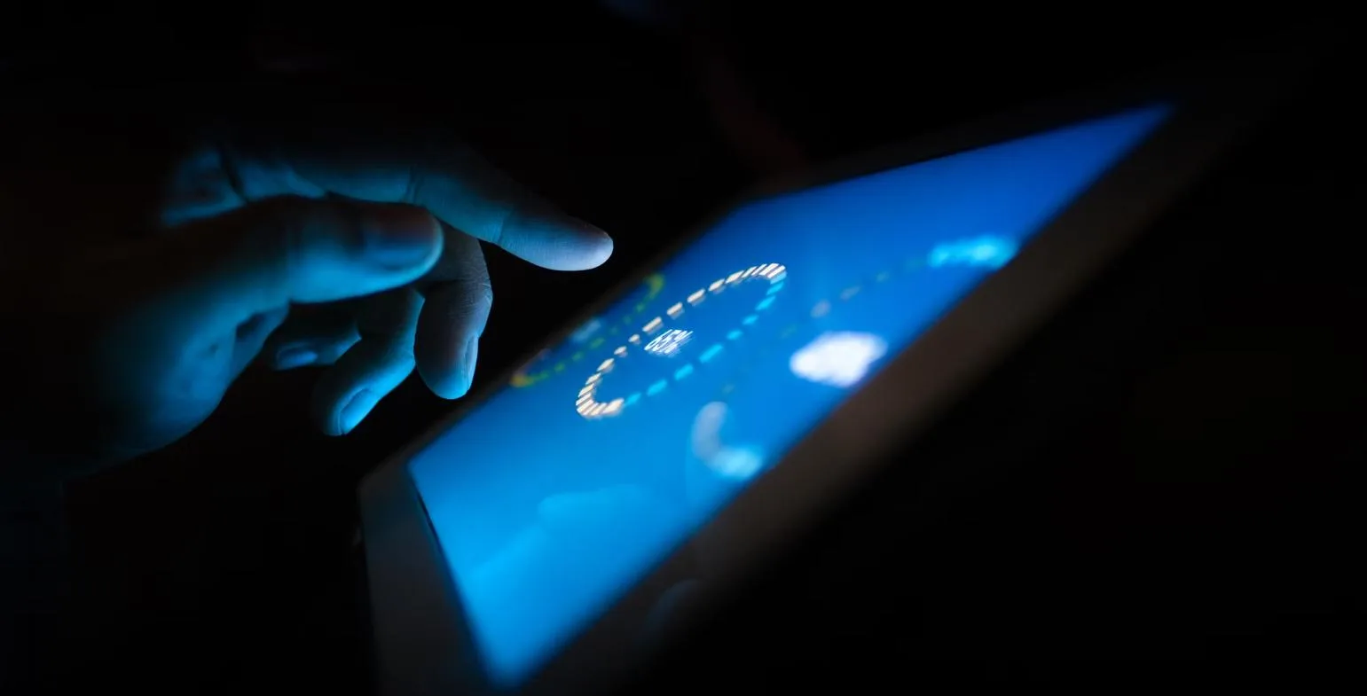 Finger touching a glowing blue tablet screen showing a circular data dial