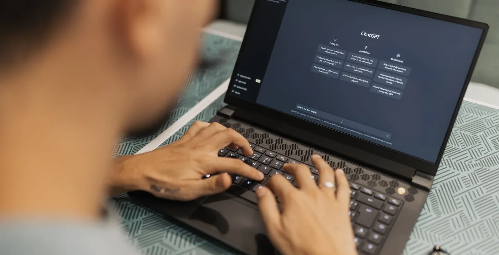 Person typing brand questions into an AI assistant on a laptop to audit what AI says about their brand