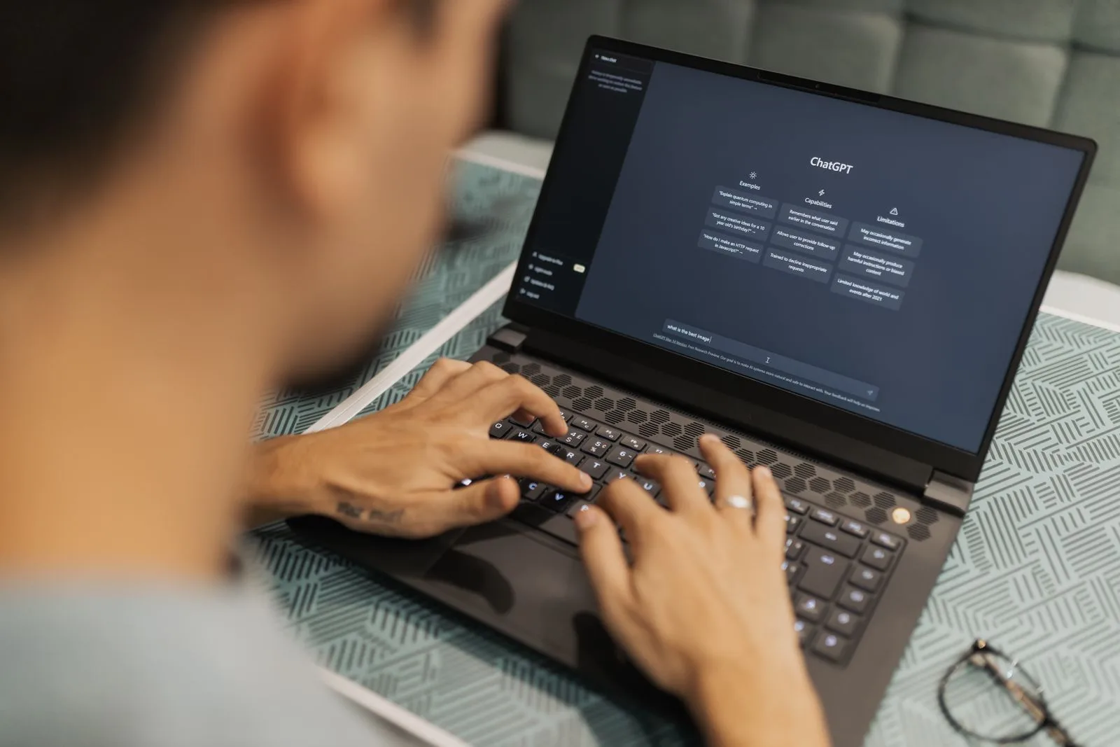Person typing brand questions into an AI assistant on a laptop to audit what AI says about their brand